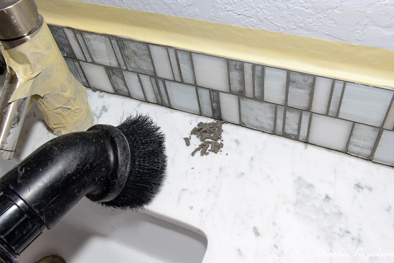 Vacuum the mess up and lightly wipe the tile down again with a sponge.
