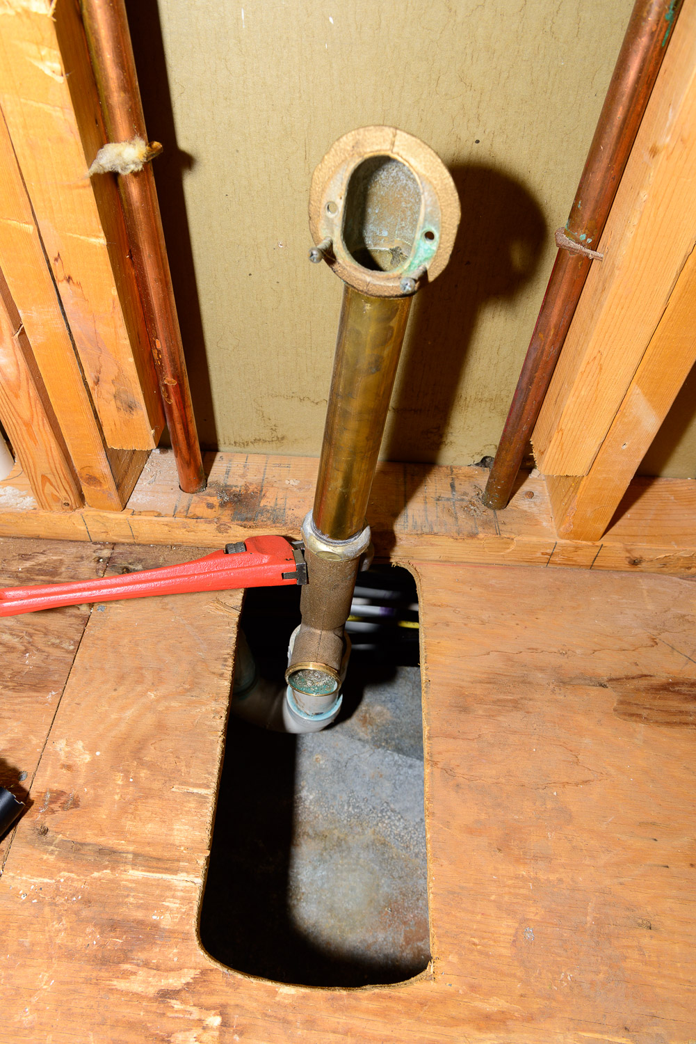 Using a pipe wrench to unscrew the threaded PVC fitting on the P trap