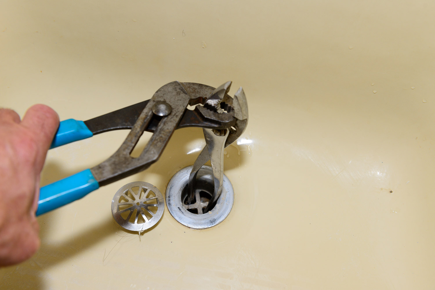 Instead of buying a tool to rotate the drain fitting you can stick your pliers handle in the drain and unscrew it.