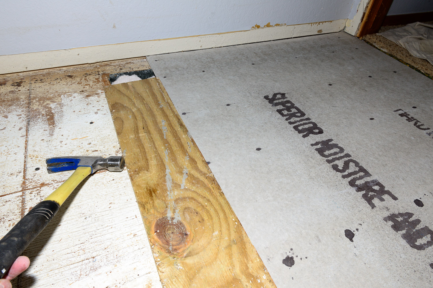 I tapped on the piece of plywood to push the board under the door frame