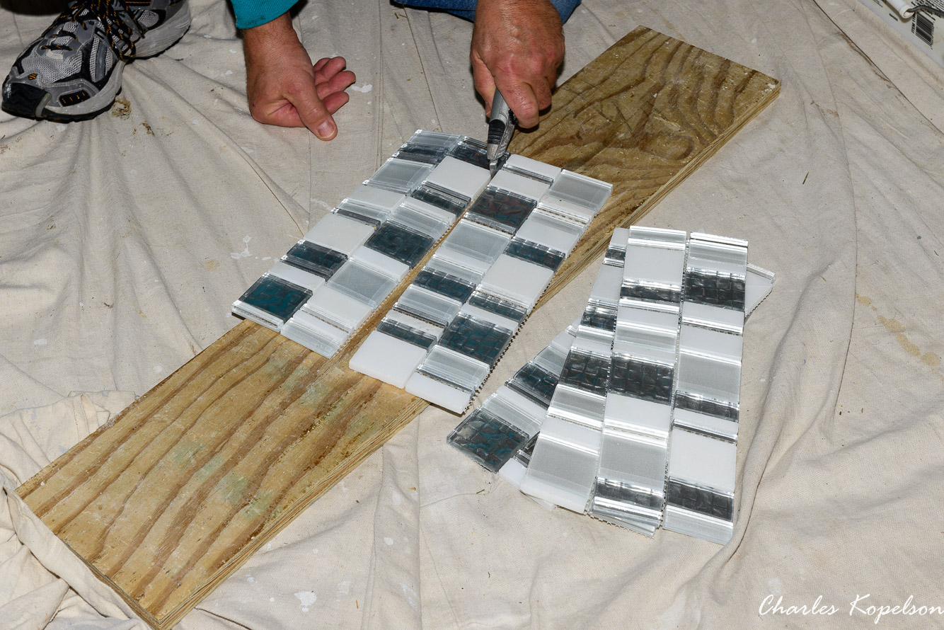 This is a 12x12 mosaic tile I'm using to make the accent stripe. I want the tiles in the stripe to be vertical to offset the large horizontal tile in the shower.  I'm using a razor knife to cut the backing so I get 3 strips from each piece